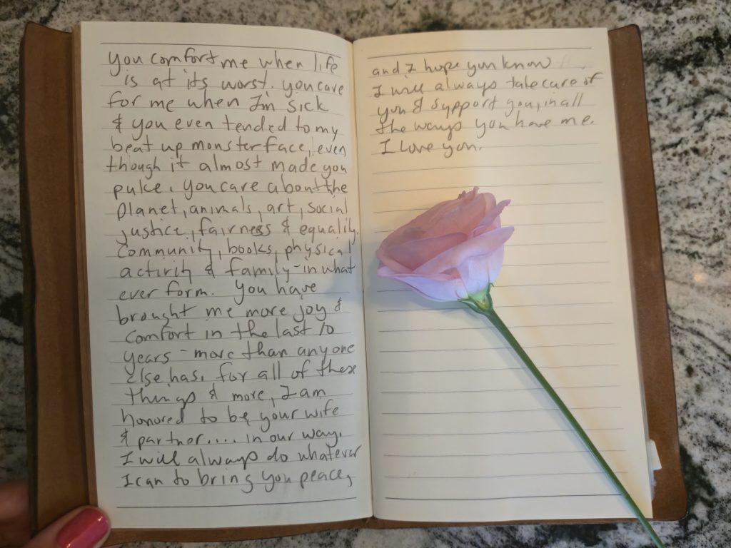 The second and third pages of her vows, with a pink flower laid overtop.